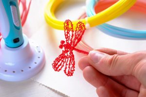 Human hand holds a red plastic dragonfly from an ABS/PLN plastic