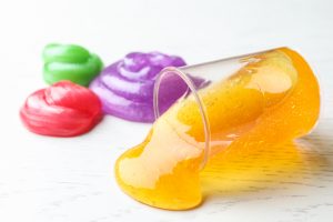 Different bright slimes on white wooden background, closeup